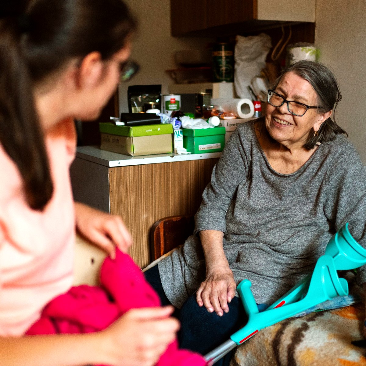 Care worker visiting an older woman at home, with a walking crutch nearby