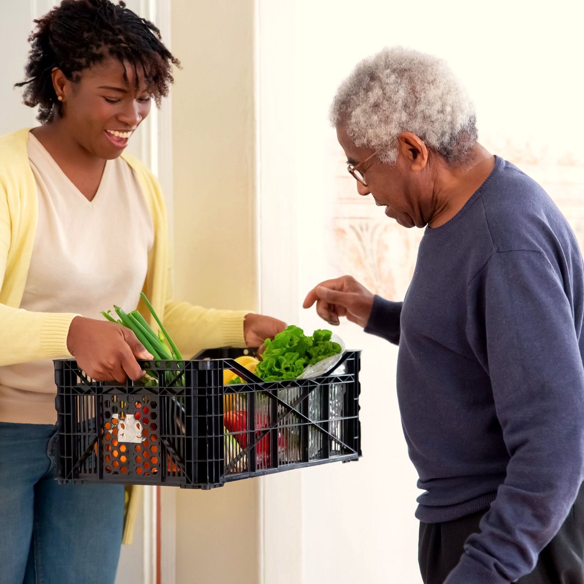 Care worker bringing a crate of shopping into a client's home